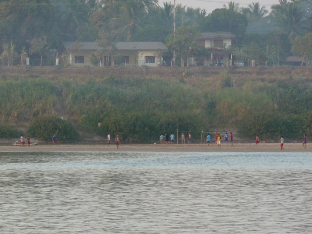 Soccer players on the Laos riverbank of the Mekong