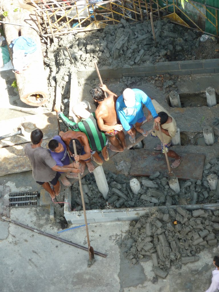 Manual work: Construction workers ramming a pillar foundation into the ground