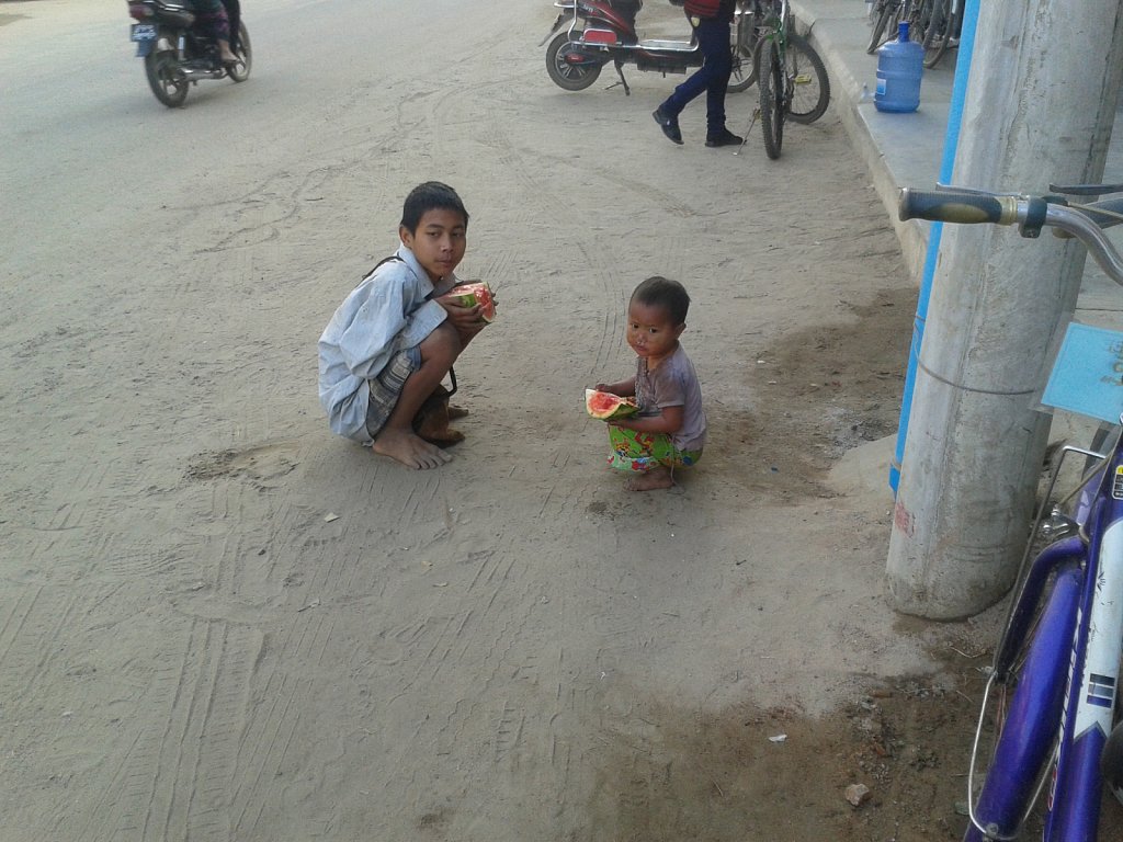 Kids eating melon on the roadside