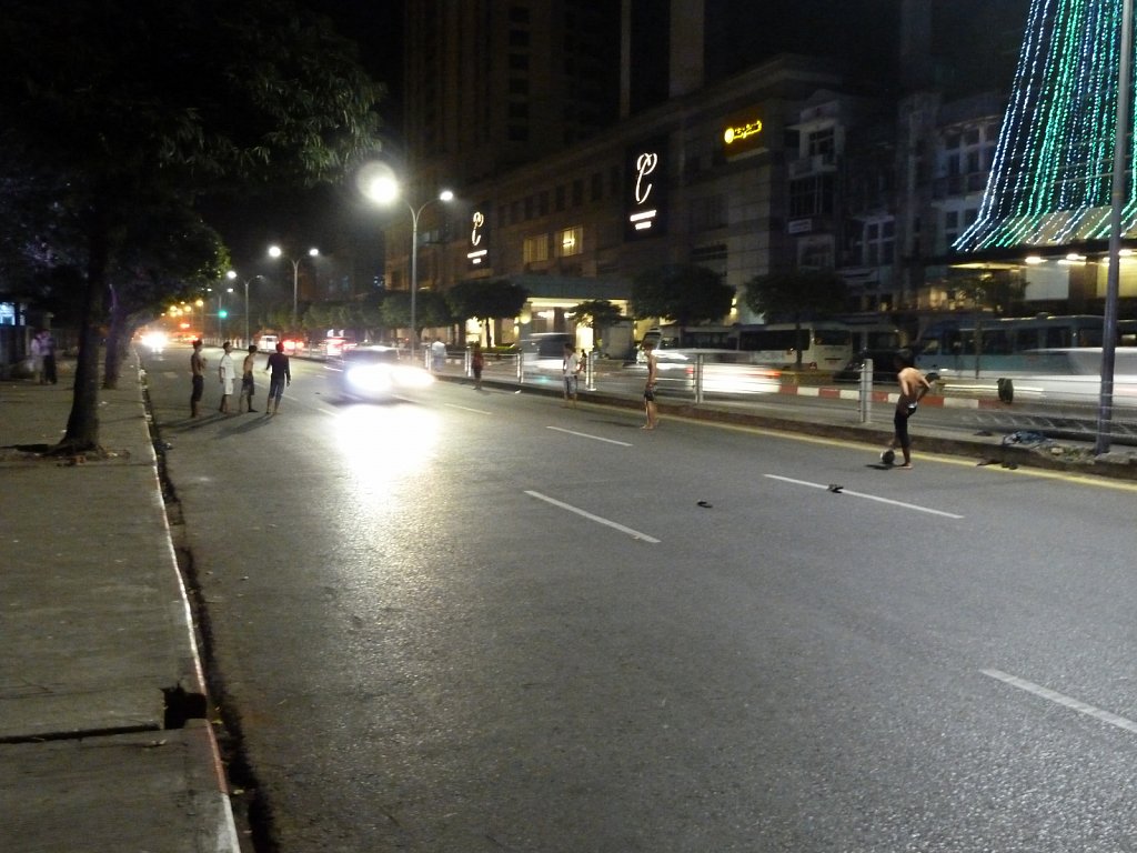 Teenagers playing soccer on a multi-lane street in Yangon at nig